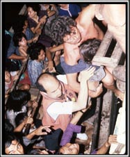 Vietnamese boat people scrambling on board a larger vessel which has stopped to pick them up